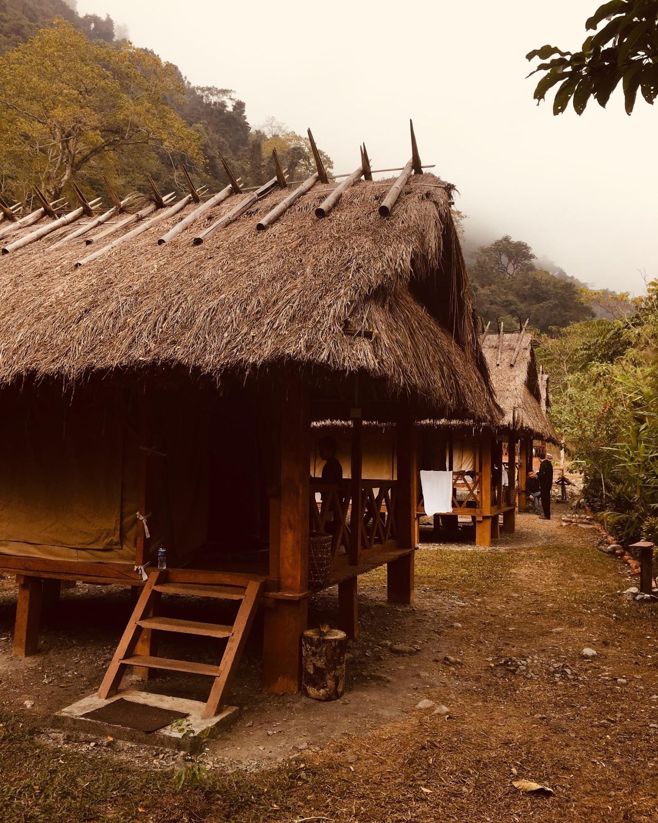 A traditional thatched hut among forested hills in Bhutan