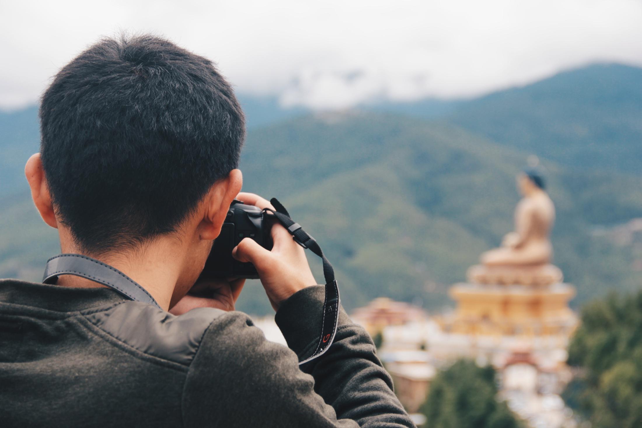 A traveler photographing Buddha Dordenma from Kuensel Phodrang
